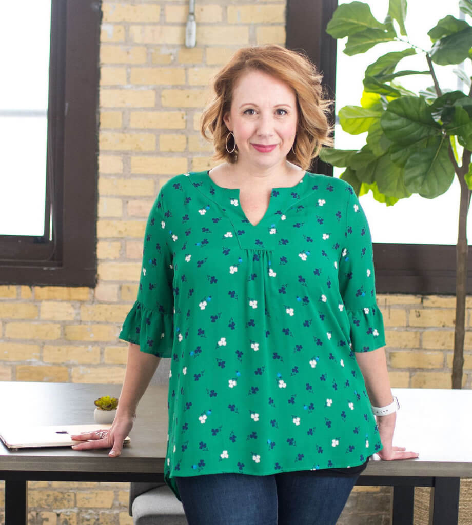 Branding Strategist Jen Fieldman stands in front of a table, smiling.