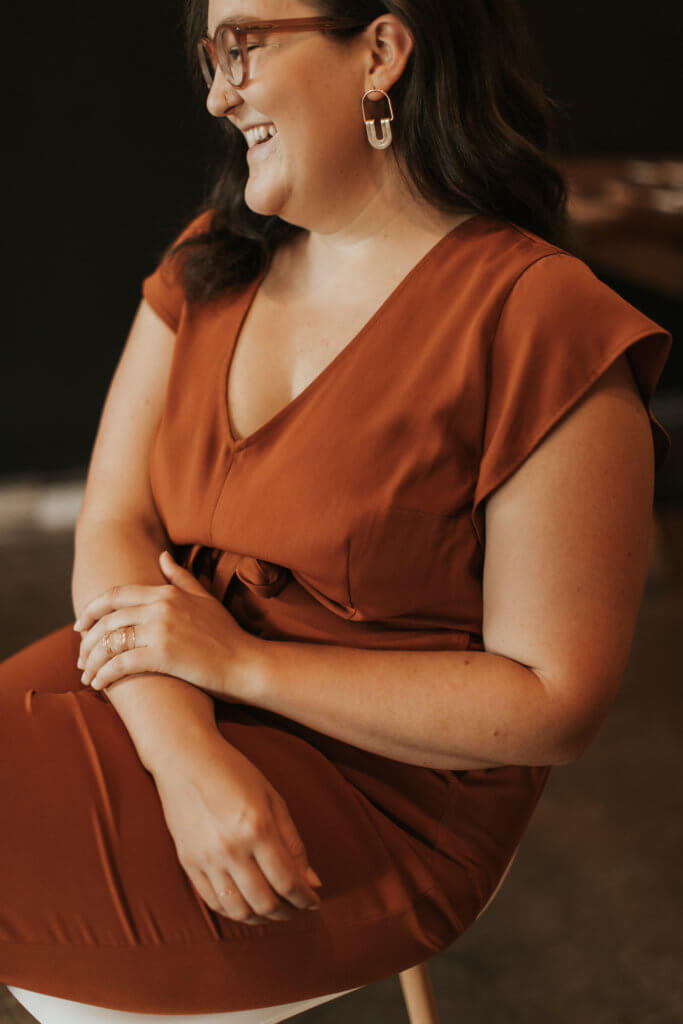 AnnaKate Auten, a self-branding expert sits on a chair in profile smiling