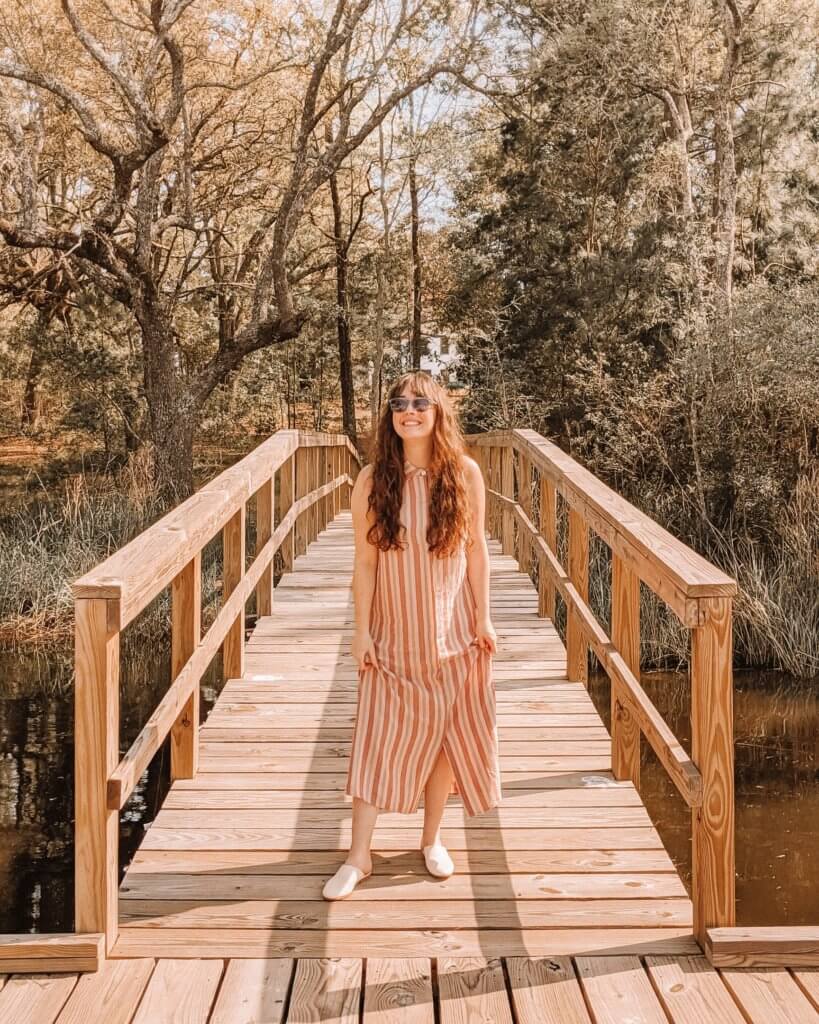Chloe Bubert, a top influencer in sustainable fashion and lifestyle, stands on a bridge in sunglasses
