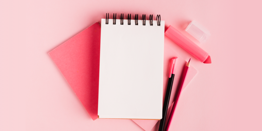 Notebook and pens on pink background