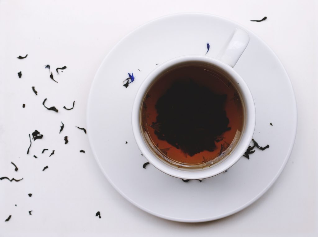 teacup on white surface with scattered tea leaves